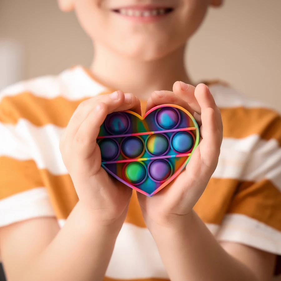 Criança segurando um brinquedo sensorial colorido em formato de coração